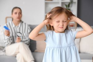 A child scratches her scalp at home, showing the visible itch and reddened skin that prompts a Mt Pleasant parent to part the hair, look for lice, and decide whether the strong reaction needs a doctor.